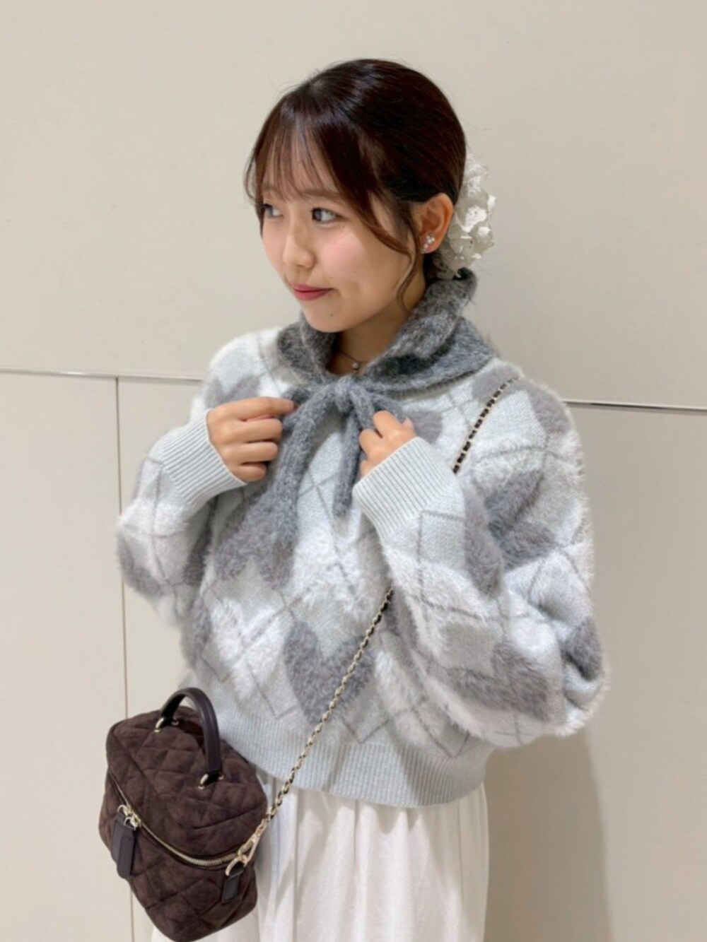 ホワイト系のスカート、グレー系のニット/セーター、ブラウン系のショルダーバッグを着用したレディースの秋コーディネートの3枚目の写真