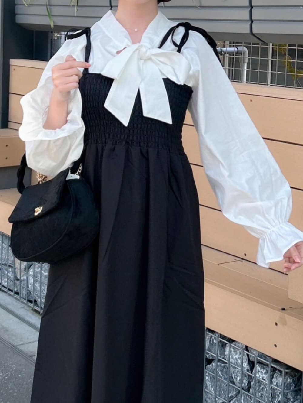 ブラック系のワンピース、ブラック系のショルダーバッグ、ホワイト系のシャツ/ブラウスを着用したレディースの冬コーディネートの2枚目の写真