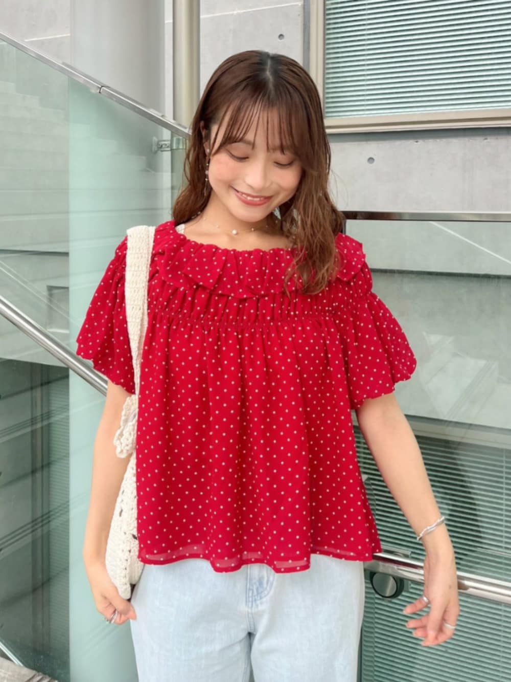ブルー系のデニムパンツ、ホワイト系のショルダーバッグ、レッド系のシャツ/ブラウスを着用したレディースの夏コーディネートの2枚目の写真
