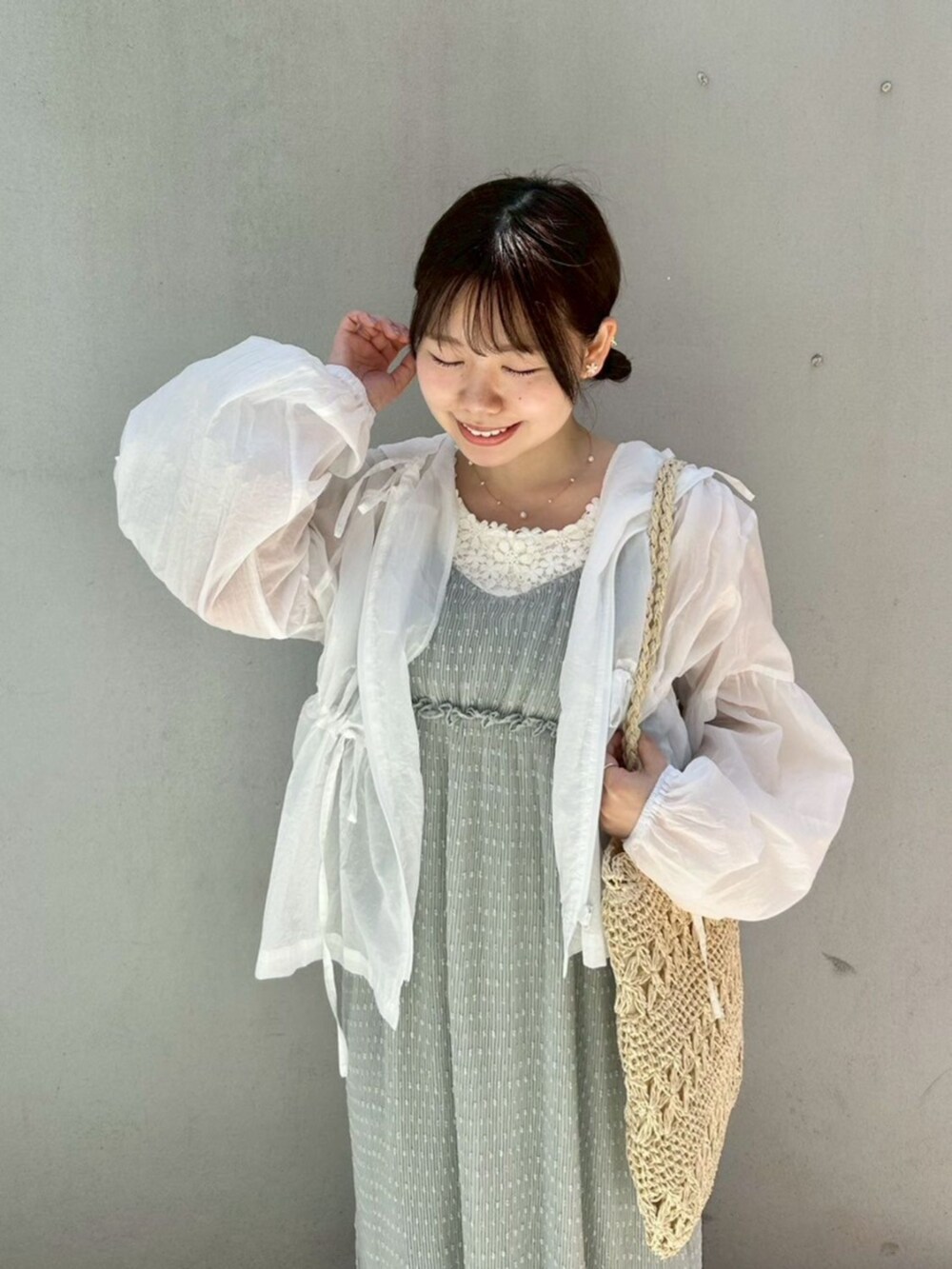 ホワイト系のタンクトップ、ホワイト系のナイロンジャケット、グリーン系のワンピースを着用したレディースの春コーディネートの2枚目の写真