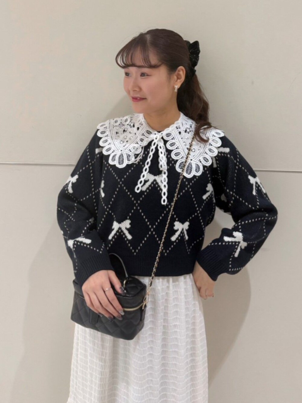 ホワイト系のスカート、ブラック系のショルダーバッグ、ブルー系のニット/セーターを着用したレディースの秋コーディネートの2枚目の写真