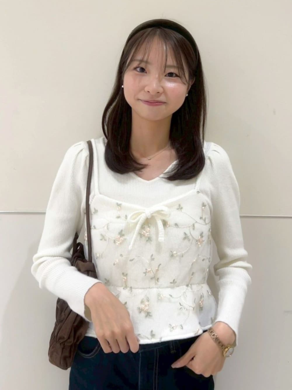 ブラウン系のショルダーバッグ、ホワイト系のニット/セーター、ホワイト系のキャミソールを着用したレディースの冬コーディネートの2枚目の写真