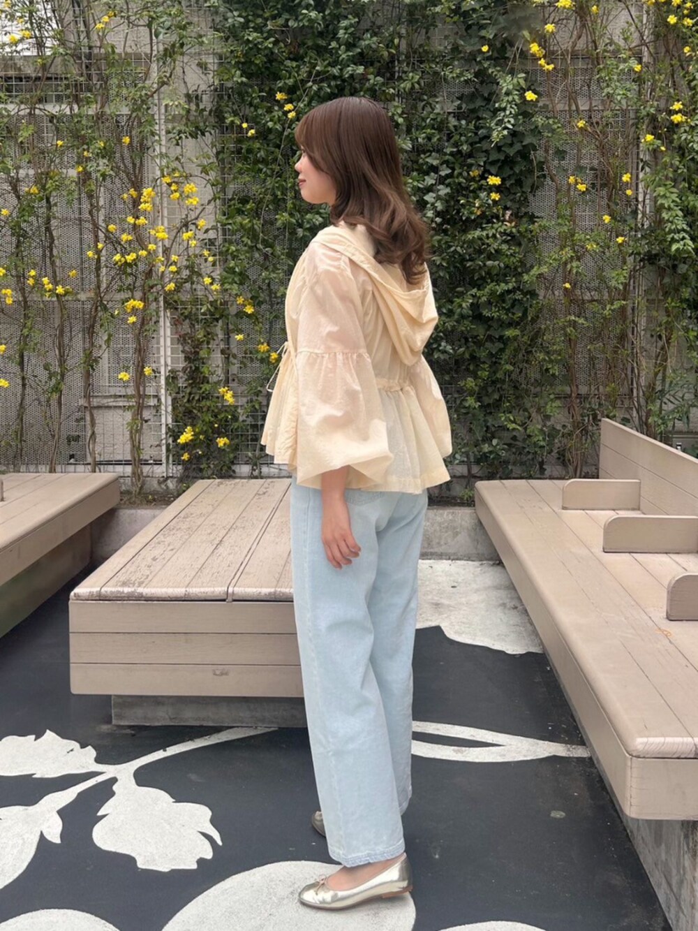 ホワイト系のキャミソール、ベージュ系のナイロンジャケット、ブルー系のデニムパンツを着用したレディースの春コーディネートの2枚目の写真