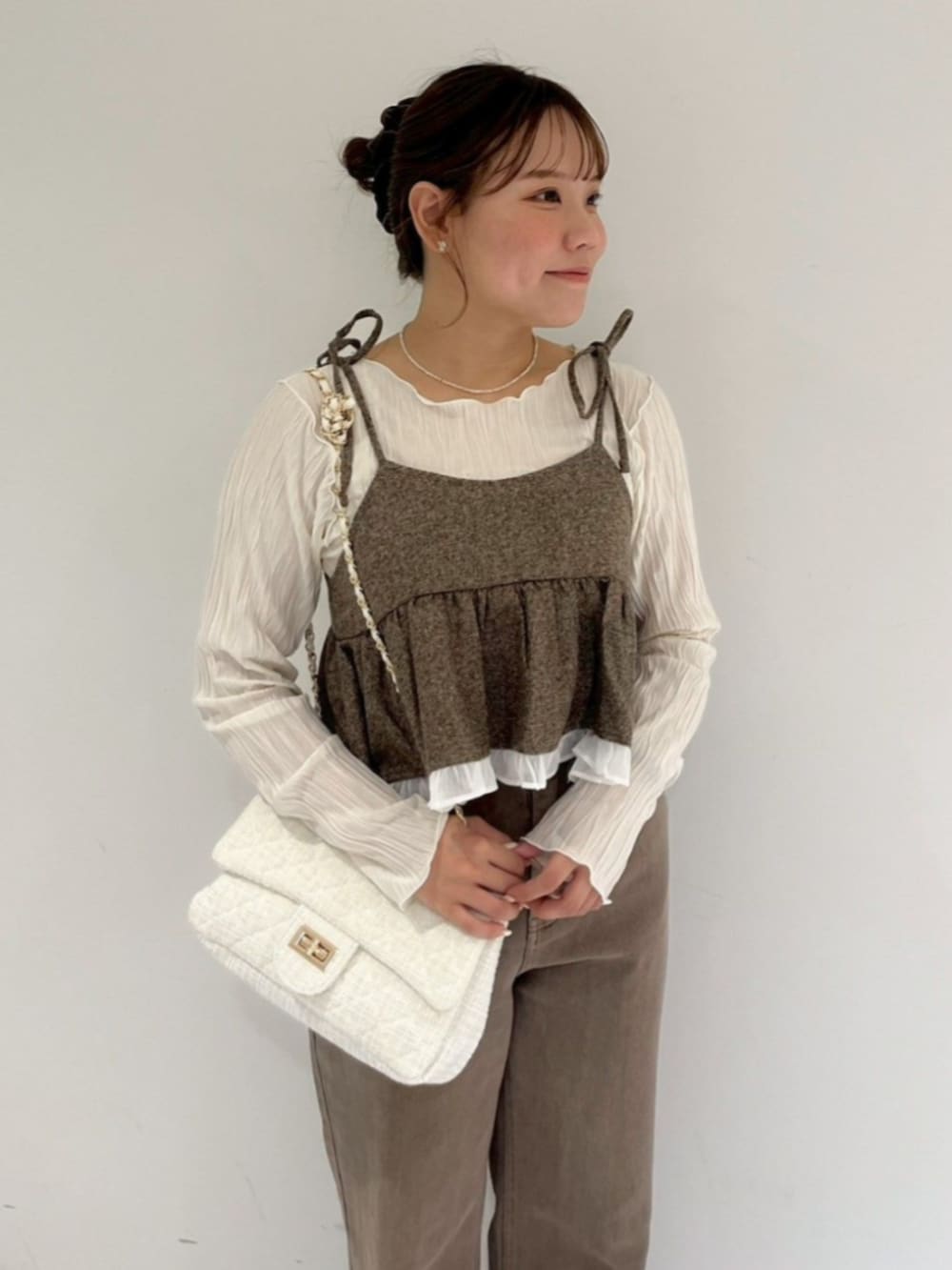 ホワイト系のTシャツ/カットソー、ブラウン系のキャミソール、ブラウン系のデニムパンツを着用したレディースの秋コーディネートの2枚目の写真