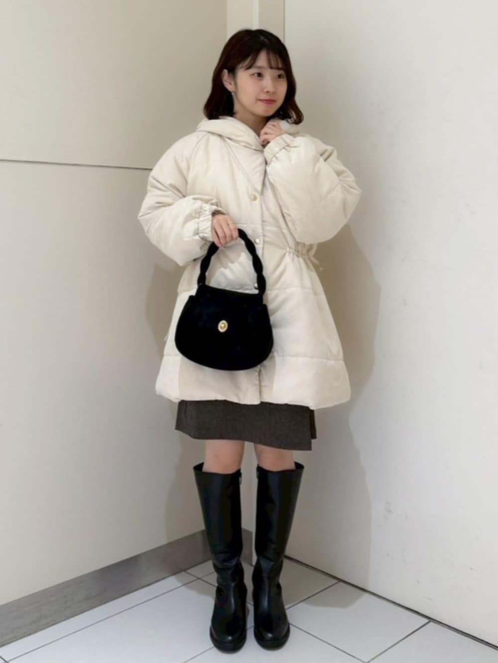 ブラック系のショルダーバッグ、ホワイト系のシャツ/ブラウス、グレー系のスカートを着用したレディースの冬コーディネートの2枚目の写真