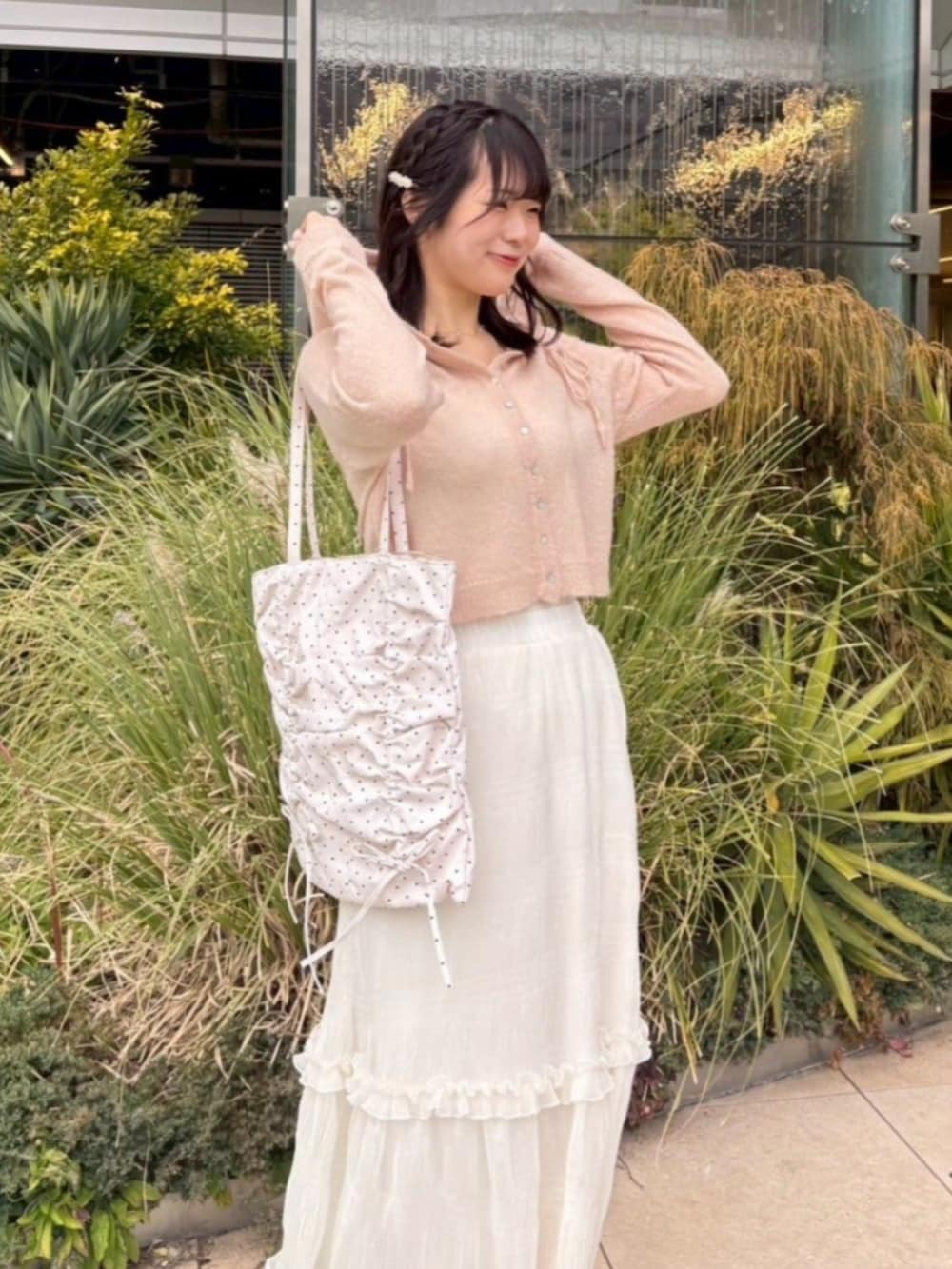 ホワイト系のスカート、ピンク系のカーディガン/ボレロ、ホワイト系のトートバッグを着用したレディースの春コーディネートの2枚目の写真