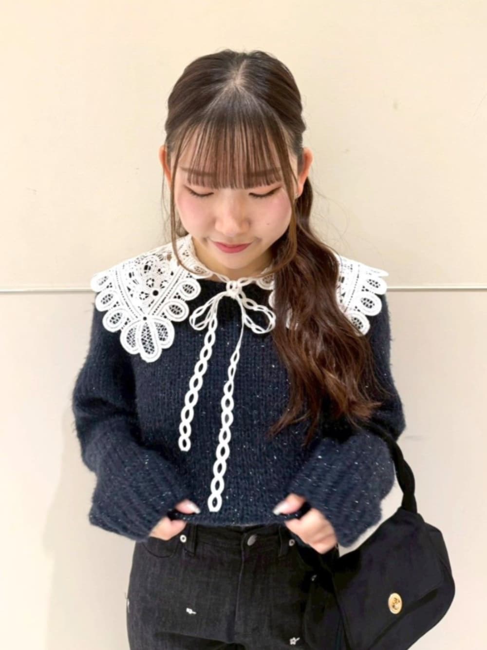 ブラック系のショルダーバッグ、ブルー系のニット/セーター、ブラック系のデニムパンツを着用したレディースの冬コーディネートの2枚目の写真