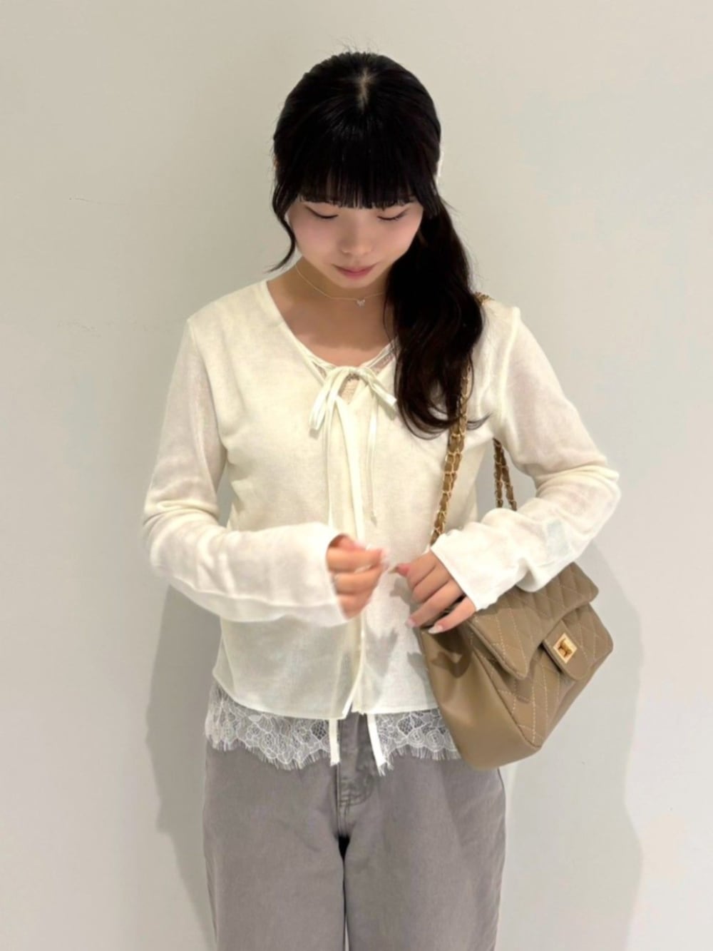ベージュ系のショルダーバッグ、ホワイト系のカーディガン/ボレロ、グレー系のデニムパンツを着用したレディースの夏コーディネートの2枚目の写真