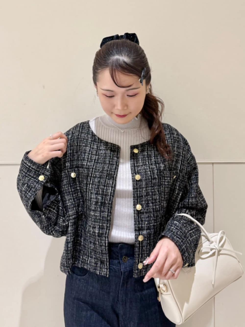 グレー系のニット/セーター、ブルー系のデニムパンツ、ブラック系のノーカラージャケットを着用したレディースの秋コーディネートの2枚目の写真