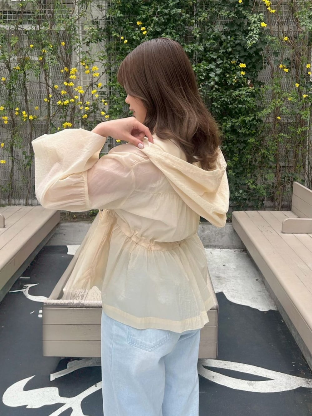 ホワイト系のキャミソール、ベージュ系のナイロンジャケット、ブルー系のデニムパンツを着用したレディースの春コーディネートの4枚目の写真