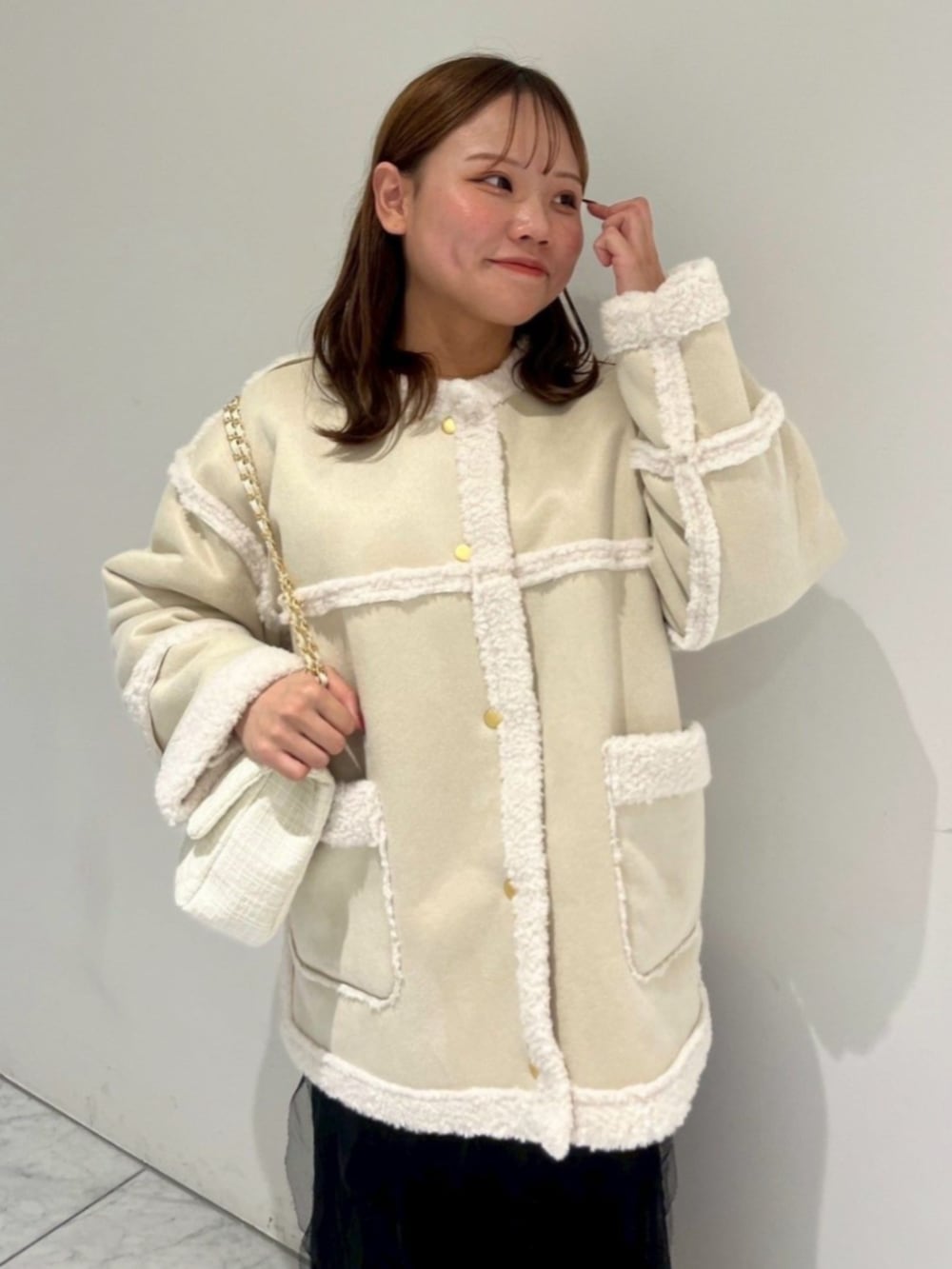 ホワイト系のショルダーバッグ、ブラック系のスカート、ホワイト系のムートンコートを着用したレディースの秋コーディネートの4枚目の写真