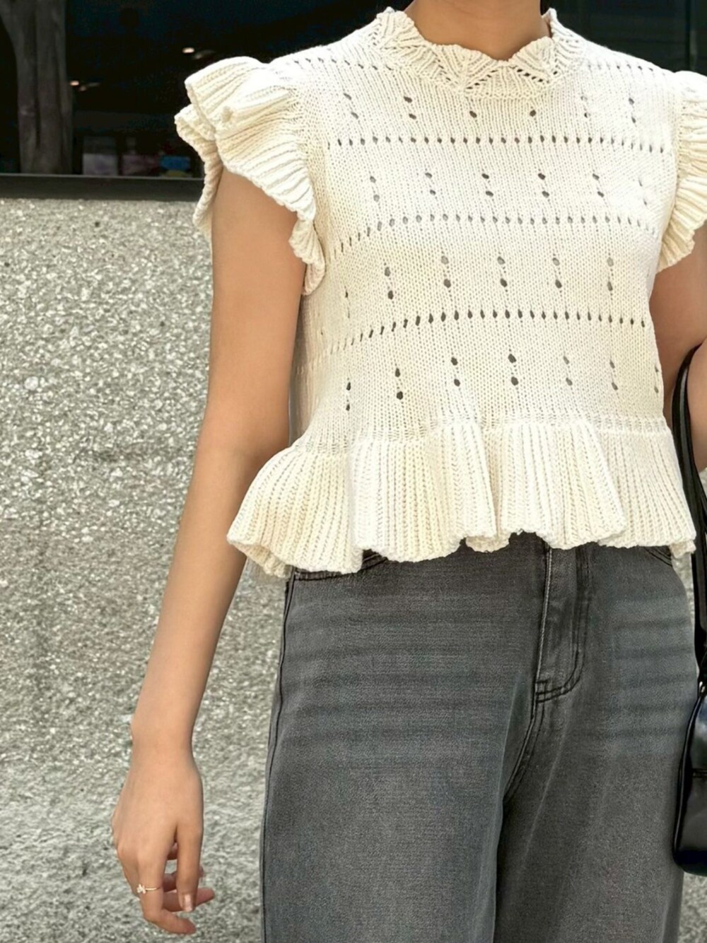 ホワイト系のニット/セーター、ブラック系のショルダーバッグ、ブラック系のデニムパンツを着用したレディースの春コーディネートの2枚目の写真