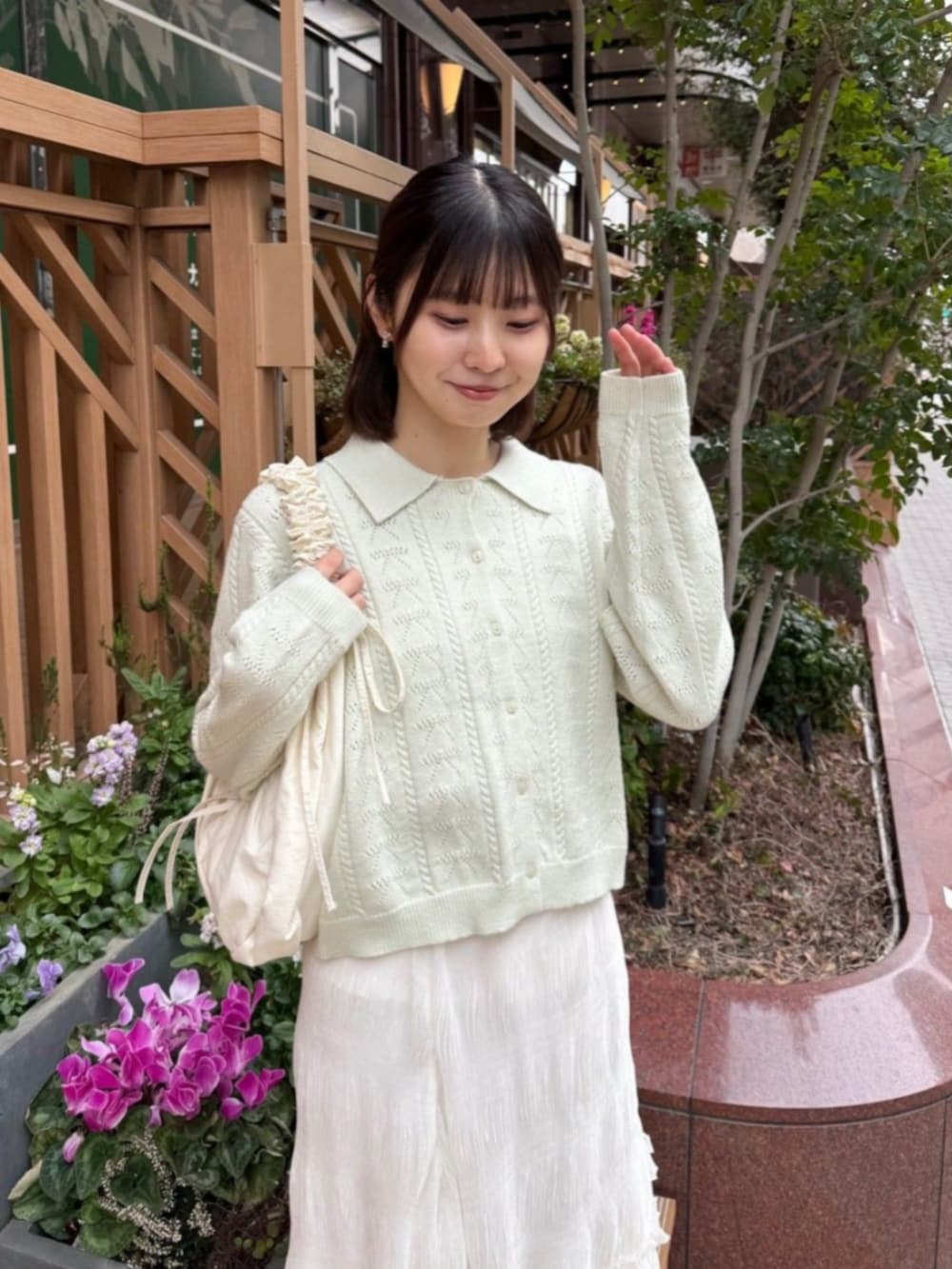 ホワイト系のショルダーバッグ、ホワイト系のスカート、グリーン系のカーディガン/ボレロを着用したレディースの春コーディネートの2枚目の写真