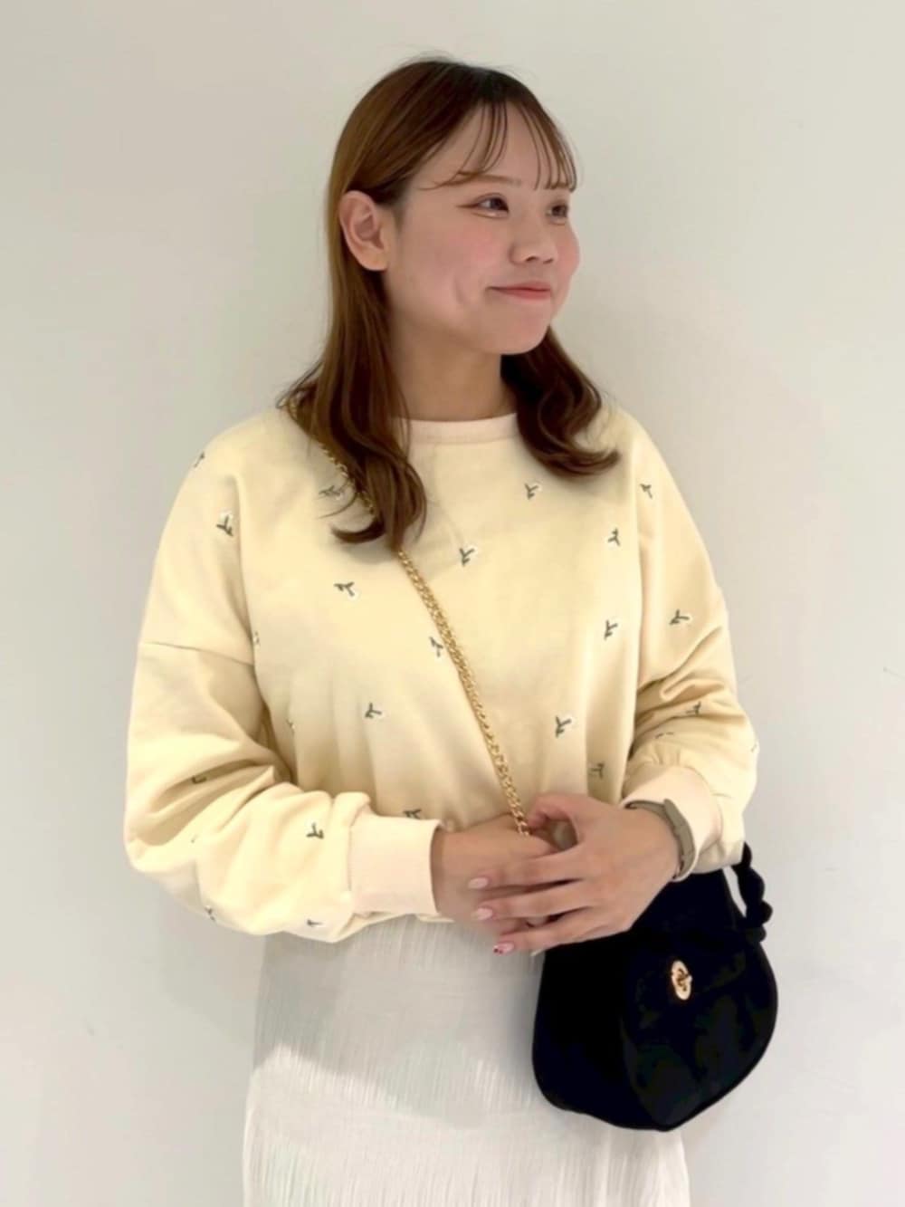 ブラック系のショルダーバッグ、ホワイト系のスカート、イエロー系のスウェットを着用したレディースの冬コーディネートの2枚目の写真