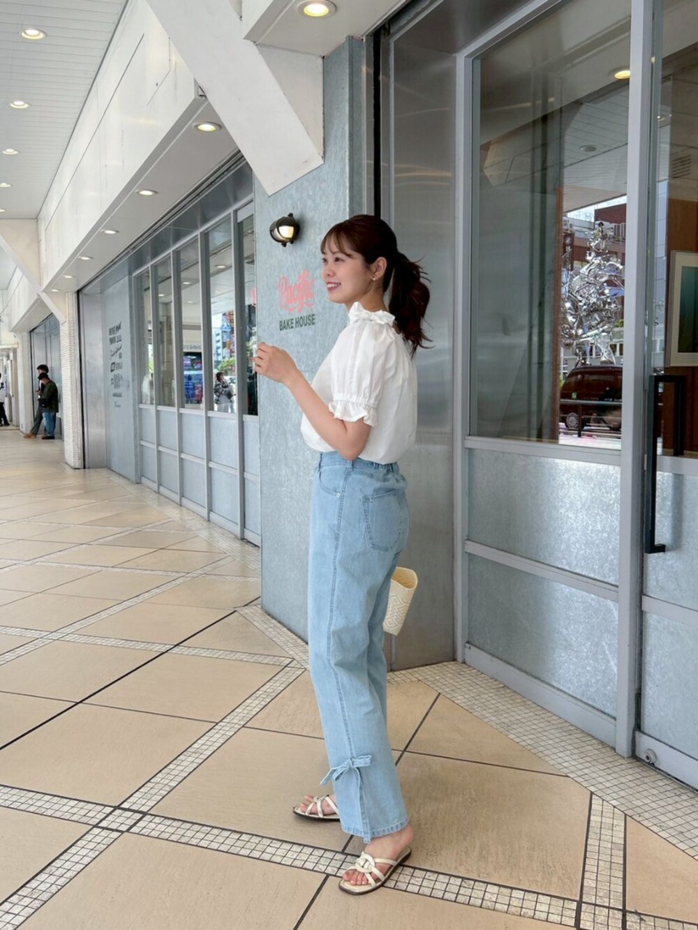 ブルー系のデニムパンツ、ホワイト系のシャツ/ブラウス、ゴールド系のピアス（片耳用）を着用したレディースの春コーディネートの2枚目の写真