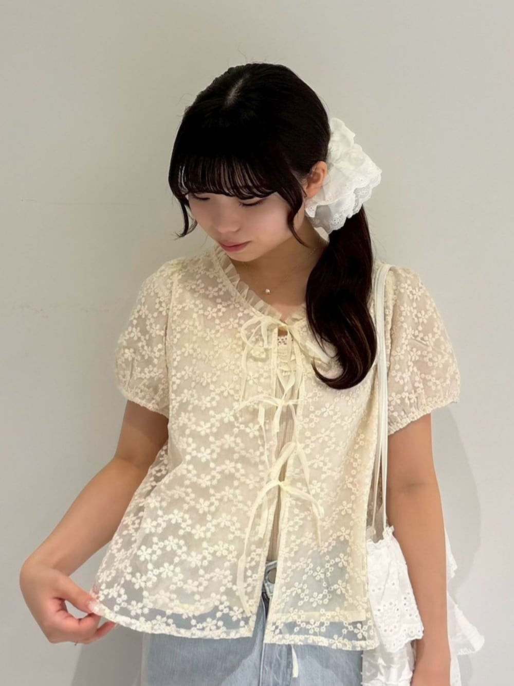 ブルー系のデニムパンツ、ホワイト系のトートバッグ、ホワイト系のシャツ/ブラウスを着用したレディースの夏コーディネートの2枚目の写真