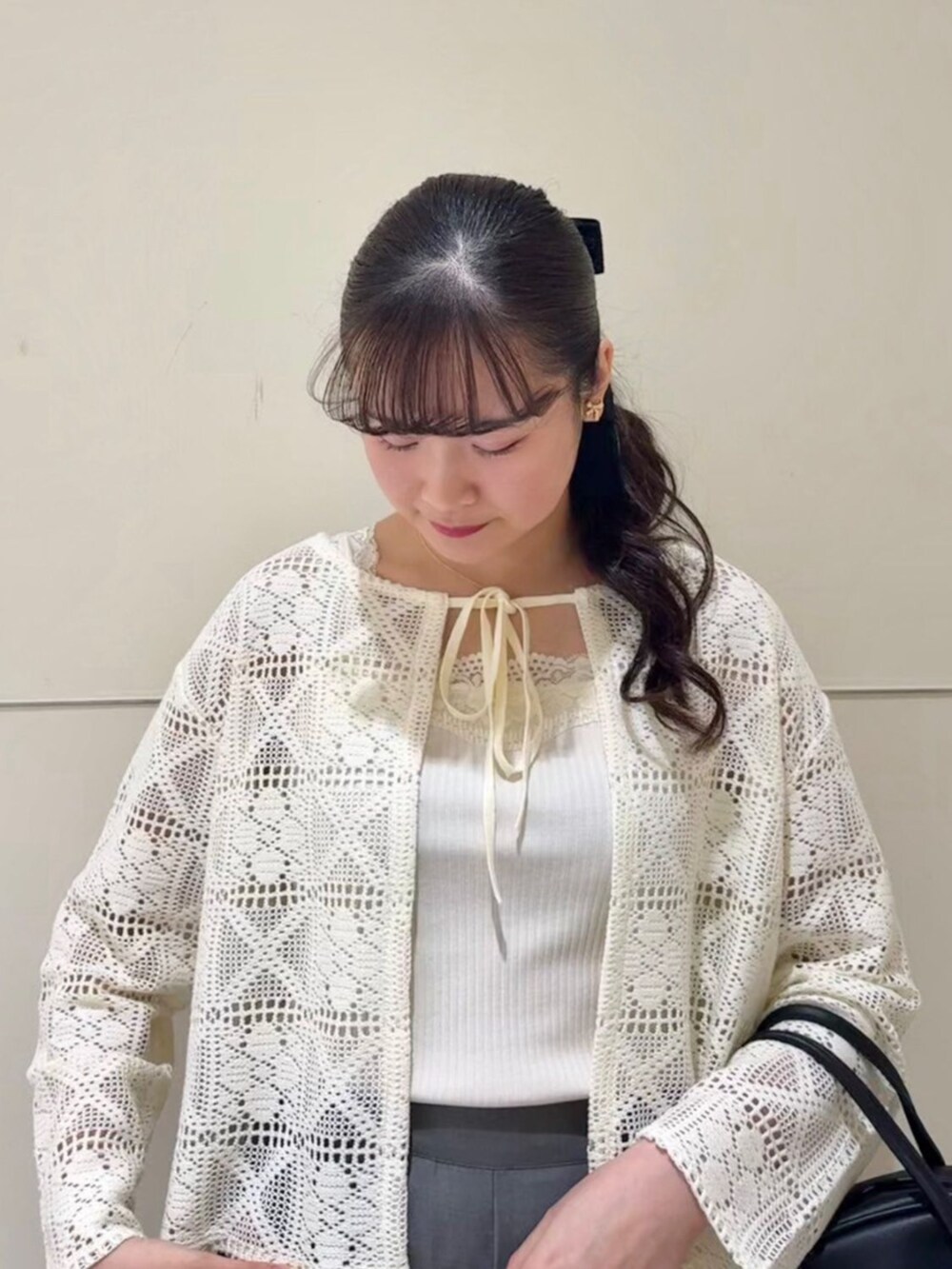 ホワイト系のキャミソール、ブラック系のハンドバッグ、ホワイト系のカーディガン/ボレロを着用したレディースの春コーディネートの2枚目の写真