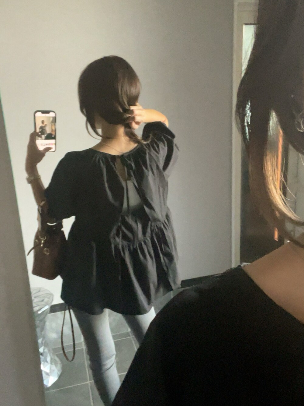 ブラック系のシャツ/ブラウス、グレー系のデニムパンツ、ブラウン系のバッグを着用したレディースの秋コーディネートの2枚目の写真