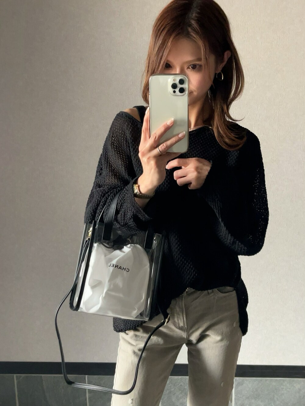 ブラック系のニット/セーター、ベージュ系のデニムパンツ、ブラック系のバッグを着用したレディースの春コーディネートの2枚目の写真