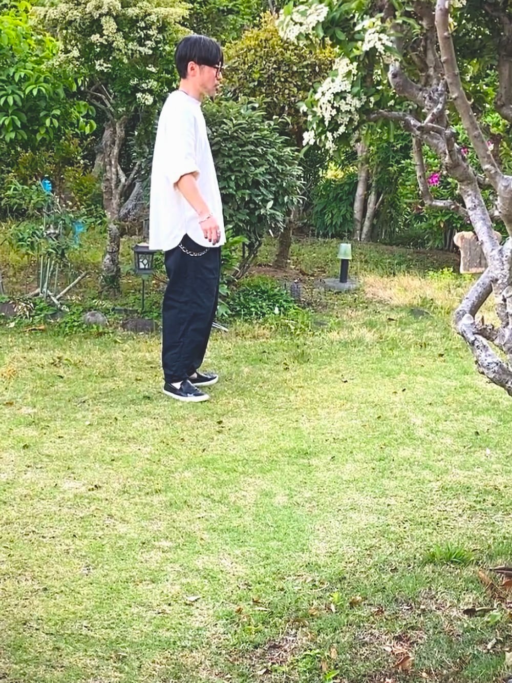 ホワイト系のTシャツ/カットソー、ブラック系のチノパンツ、ブラック系のスリッポンを着用したメンズの春コーディネートの2枚目の写真