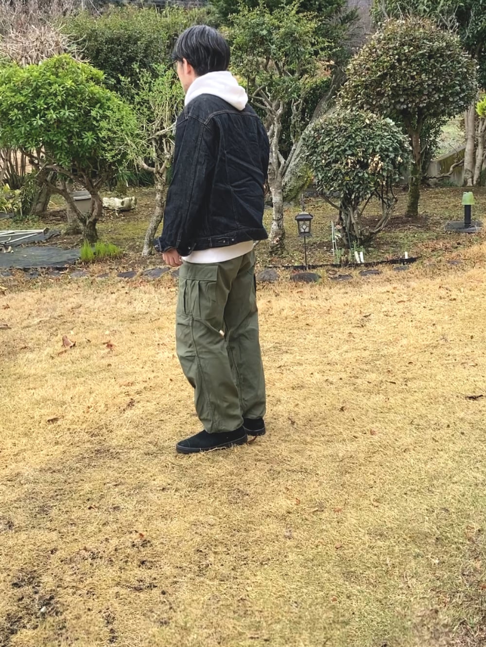 ベージュ系のパーカー、ブラック系のデニムジャケット、グリーン系のカーゴパンツを着用したメンズの春コーディネートの4枚目の写真