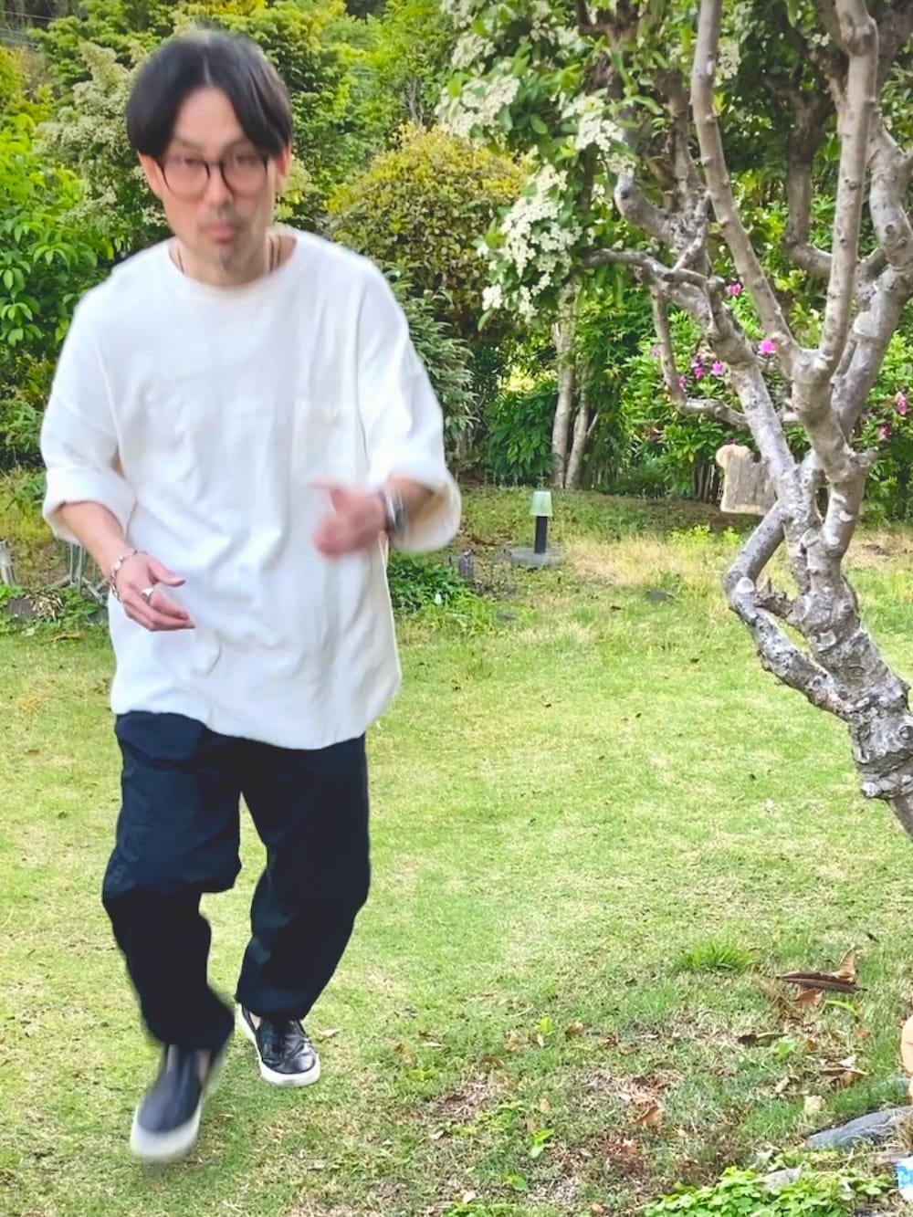 ホワイト系のTシャツ/カットソー、ブラック系のチノパンツ、ブラック系のスリッポンを着用したメンズの春コーディネートの4枚目の写真