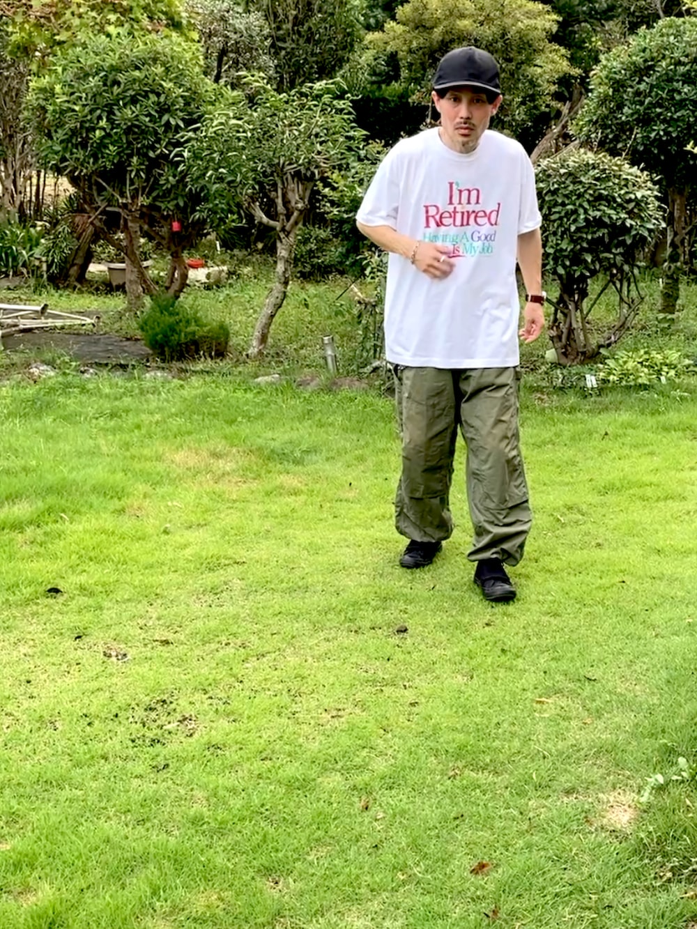 ホワイト系のTシャツ/カットソー、グリーン系のカーゴパンツ、ブラック系のスニーカーを着用したメンズの夏コーディネートの3枚目の写真