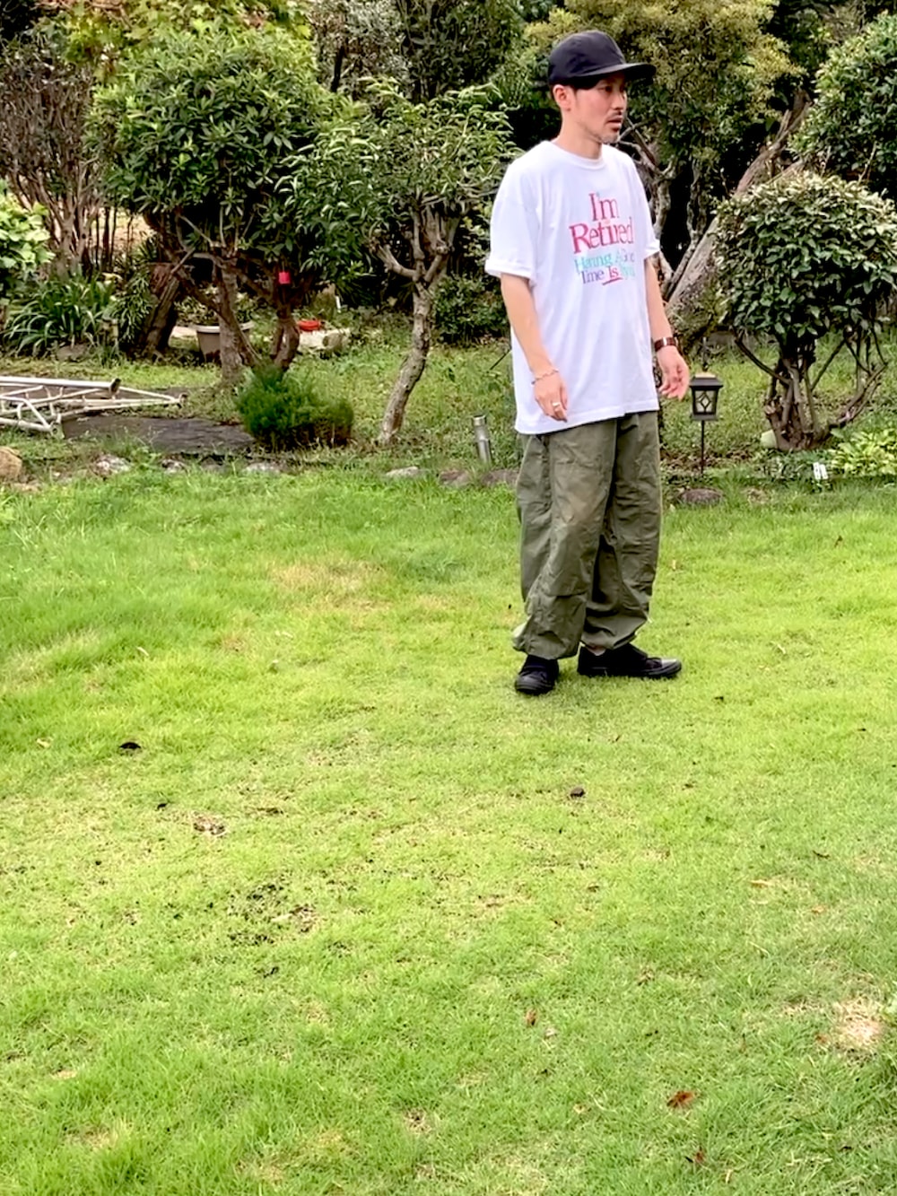 ホワイト系のTシャツ/カットソー、グリーン系のカーゴパンツ、ブラック系のスニーカーを着用したメンズの夏コーディネートの2枚目の写真
