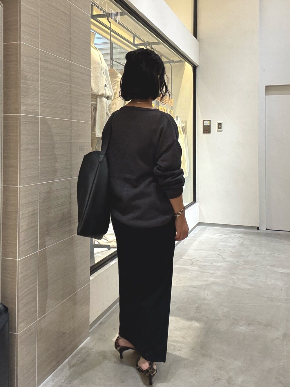 グレー系のニット/セーター、ブラック系のスカート、イエロー系のパンプスを着用したレディースの春コーディネートの3枚目の写真