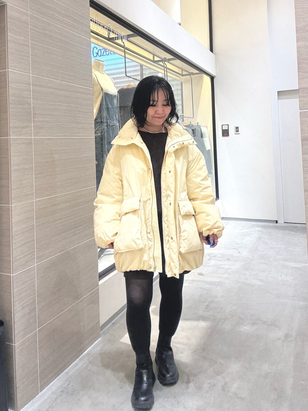 イエロー系のダウンジャケット/コート、ブラウン系のその他パンツ、ブラック系のブーツを着用したレディースの秋コーディネートの2枚目の写真