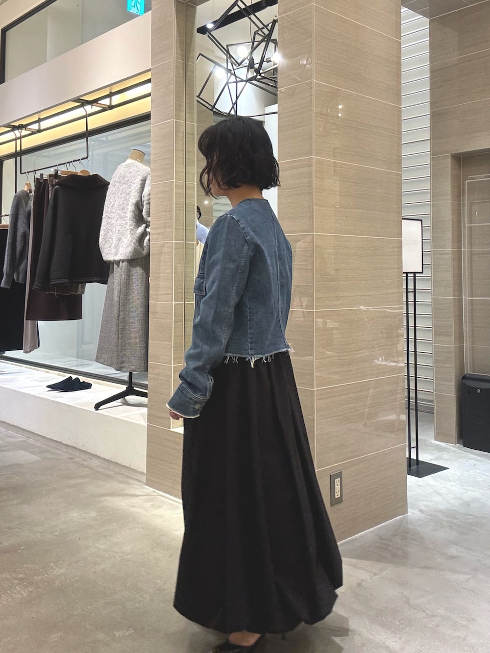 ブルー系のデニムジャケット、ブラック系のスカート、グレー系のショルダーバッグを着用したレディースの冬コーディネートの2枚目の写真