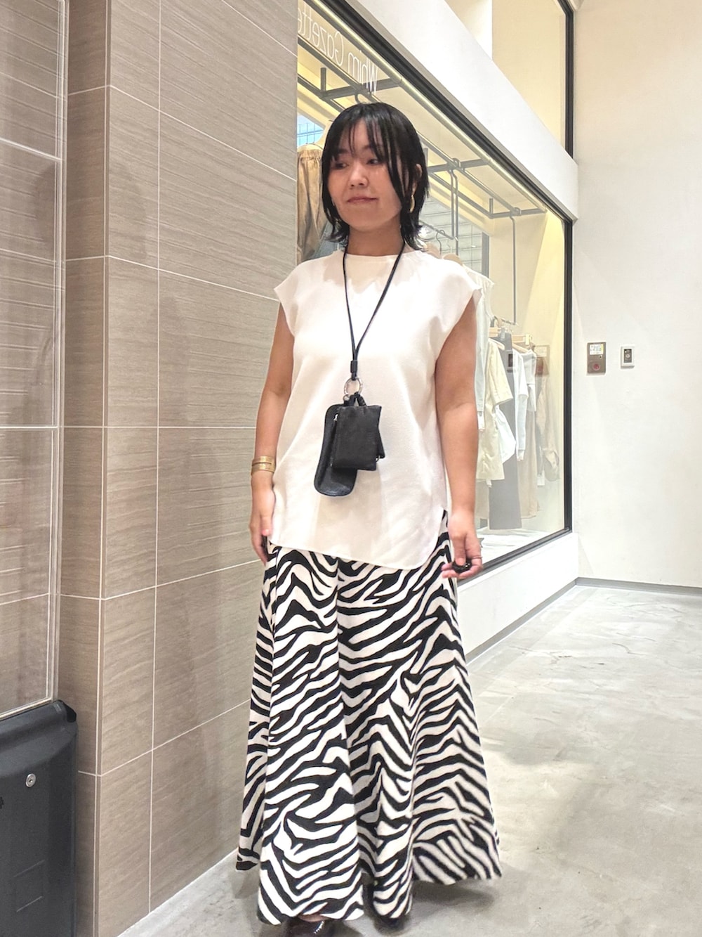 ホワイト系のシャツ/ブラウス、ホワイト系のスカート、ブラウン系のパンプスを着用したレディースの夏コーディネートの2枚目の写真