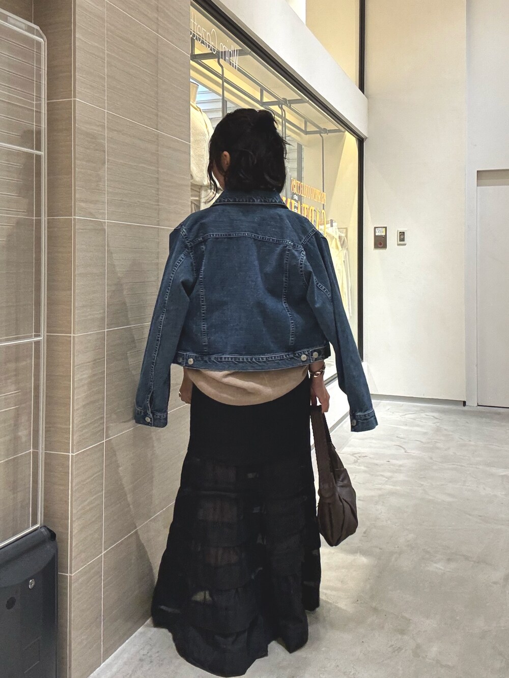 ブラック系のスカート、ブラウン系のショルダーバッグ、ブルー系のデニムジャケットを着用したレディースの冬コーディネートの5枚目の写真