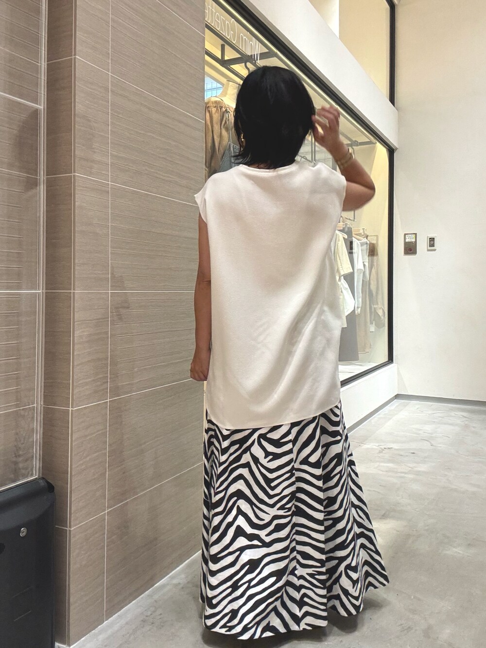 ホワイト系のシャツ/ブラウス、ホワイト系のスカート、ブラウン系のパンプスを着用したレディースの夏コーディネートの5枚目の写真