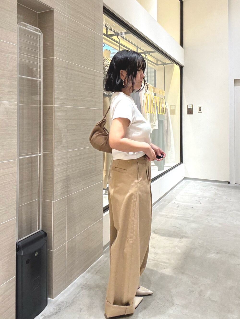 ベージュ系のチノパンツ、ホワイト系のTシャツ/カットソー、ブラウン系のショルダーバッグを着用したレディースの冬コーディネートの5枚目の写真