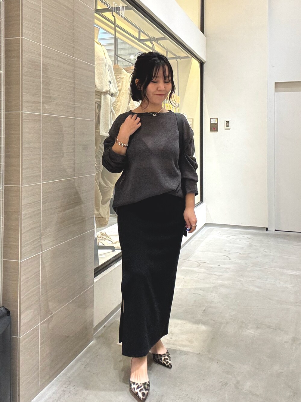 グレー系のニット/セーター、ブラック系のスカート、イエロー系のパンプスを着用したレディースの春コーディネートの6枚目の写真