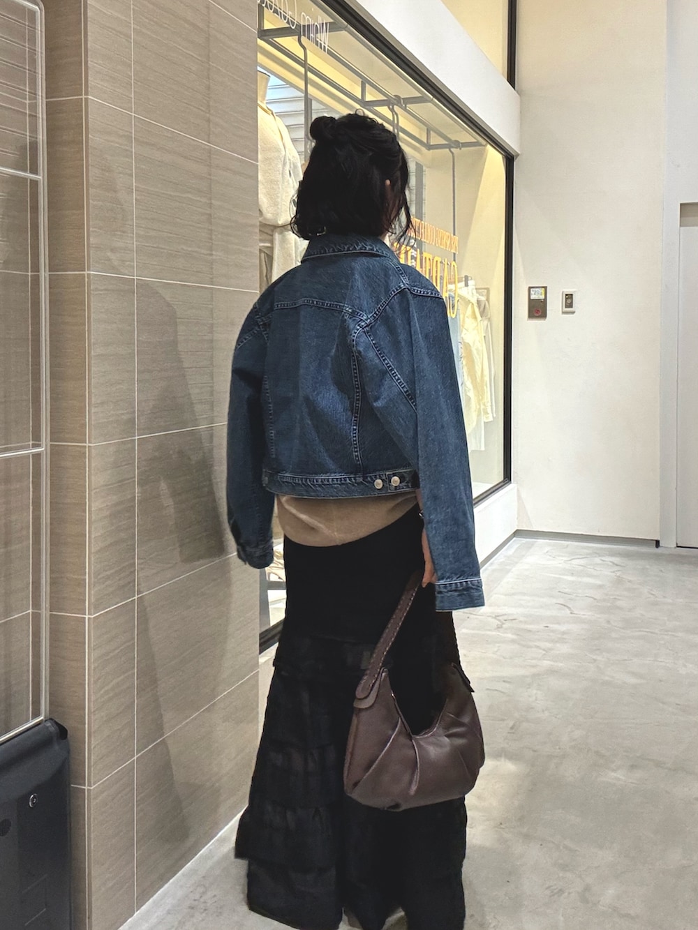 ブラック系のスカート、ブラウン系のショルダーバッグ、ブルー系のデニムジャケットを着用したレディースの冬コーディネートの6枚目の写真