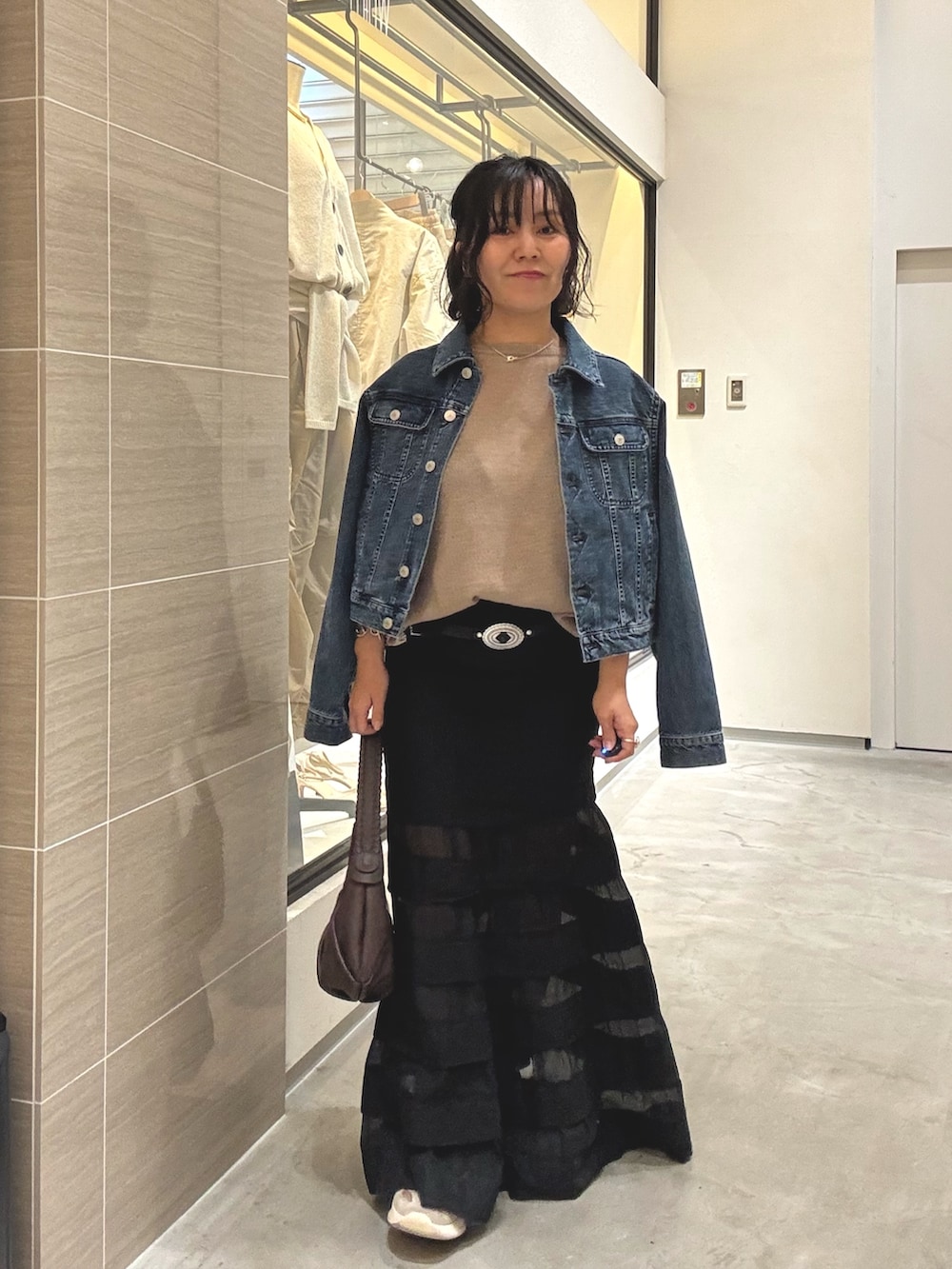 ブラック系のスカート、ブラウン系のショルダーバッグ、ブルー系のデニムジャケットを着用したレディースの冬コーディネートの3枚目の写真