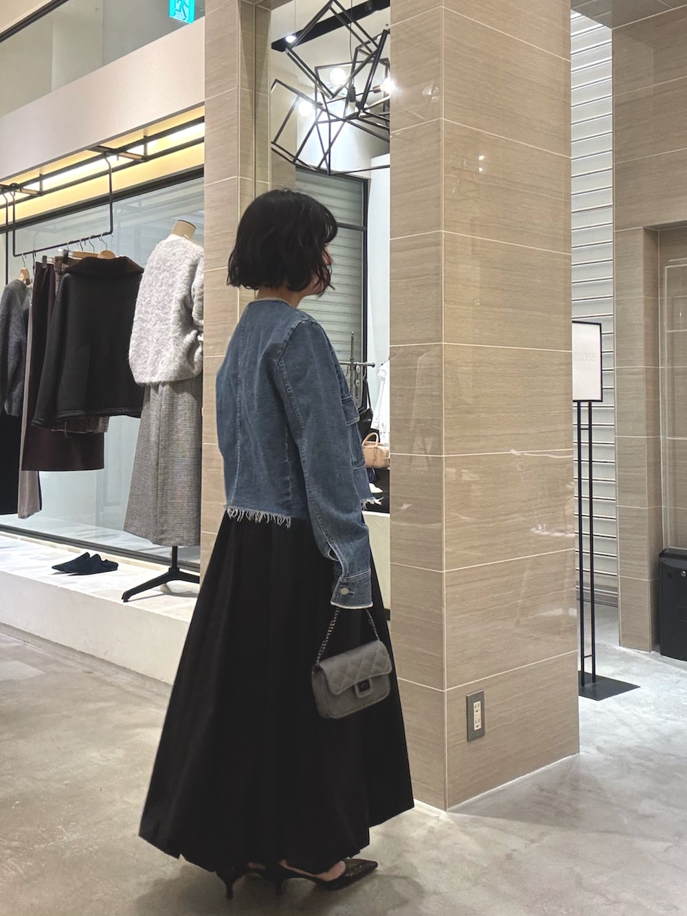 ブルー系のデニムジャケット、ブラック系のスカート、グレー系のショルダーバッグを着用したレディースの冬コーディネートの5枚目の写真