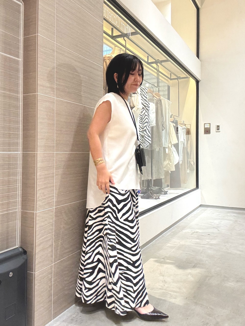 ホワイト系のシャツ/ブラウス、ホワイト系のスカート、ブラウン系のパンプスを着用したレディースの夏コーディネートの6枚目の写真