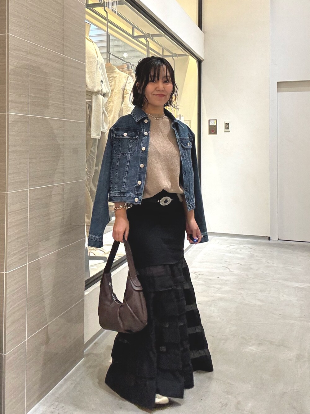 ブラック系のスカート、ブラウン系のショルダーバッグ、ブルー系のデニムジャケットを着用したレディースの冬コーディネートの7枚目の写真