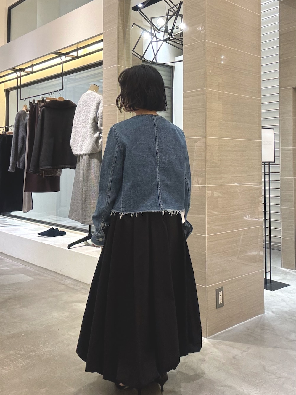 ブルー系のデニムジャケット、ブラック系のスカート、グレー系のショルダーバッグを着用したレディースの冬コーディネートの3枚目の写真