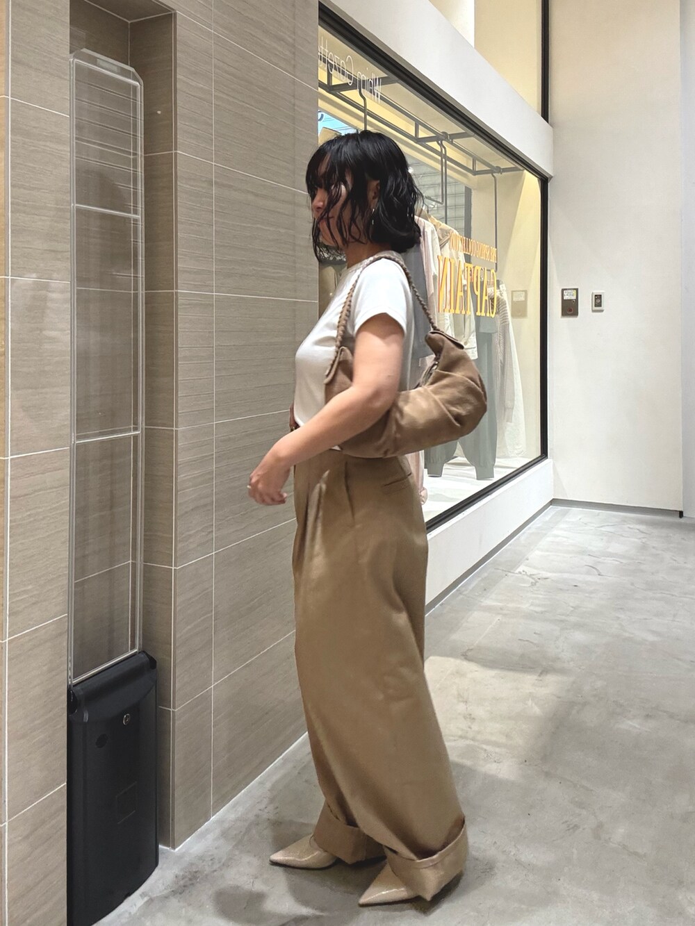 ベージュ系のチノパンツ、ホワイト系のTシャツ/カットソー、ブラウン系のショルダーバッグを着用したレディースの冬コーディネートの3枚目の写真