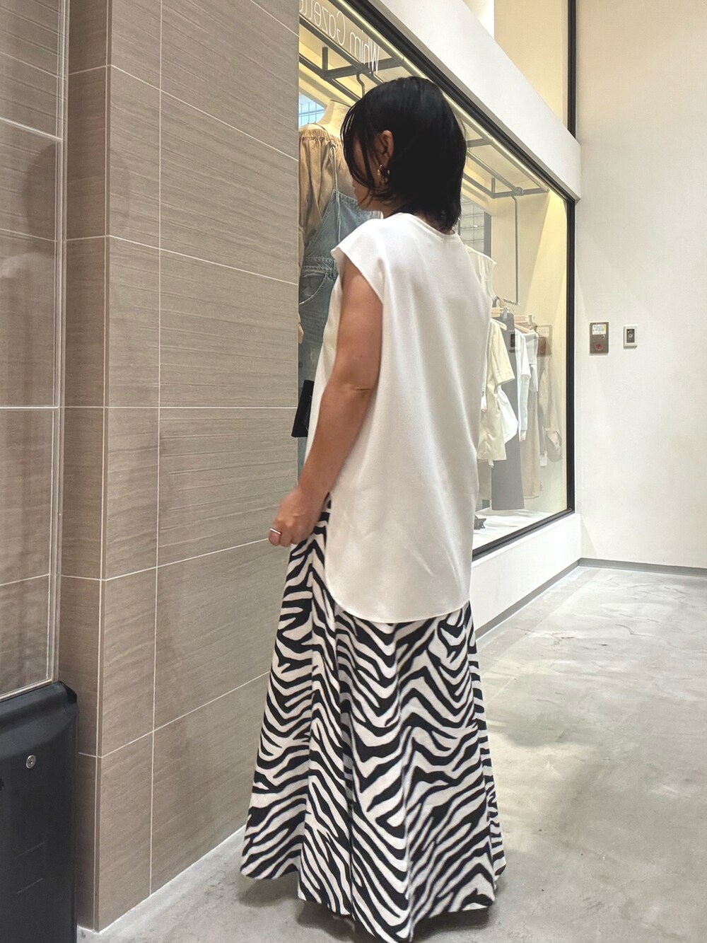 ホワイト系のシャツ/ブラウス、ホワイト系のスカート、ブラウン系のパンプスを着用したレディースの夏コーディネートの4枚目の写真