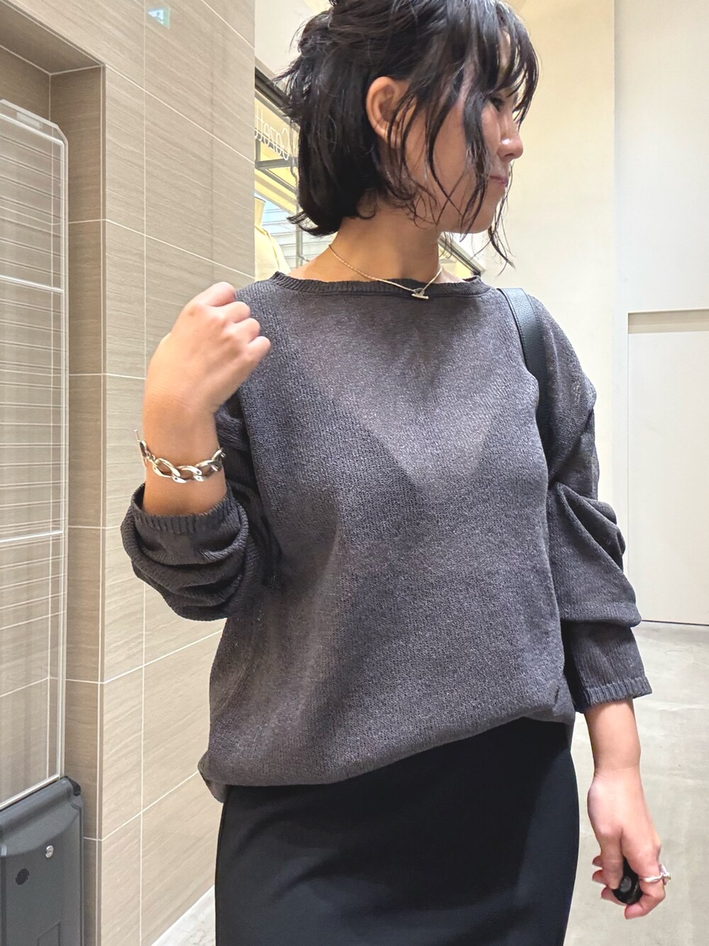 グレー系のニット/セーター、ブラック系のスカート、イエロー系のパンプスを着用したレディースの春コーディネートの7枚目の写真