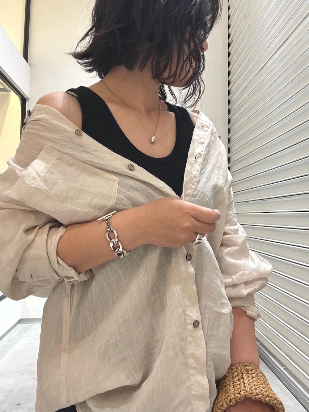 ベージュ系のシャツ/ブラウス、ブラック系のスカート、ブラック系のサンダルを着用したレディースの春コーディネートの6枚目の写真