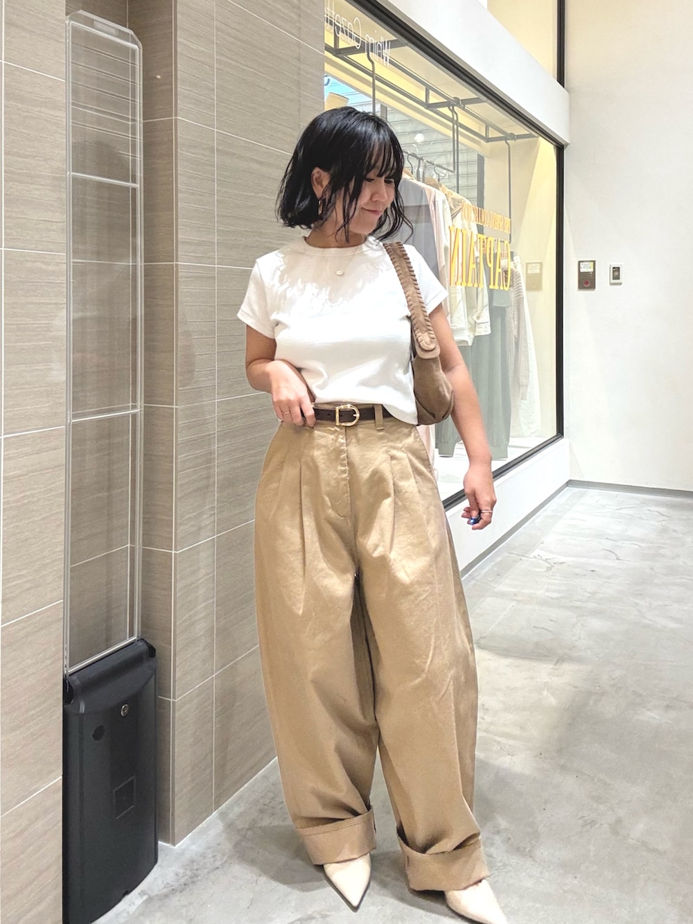 ベージュ系のチノパンツ、ホワイト系のTシャツ/カットソー、ブラウン系のショルダーバッグを着用したレディースの冬コーディネートの2枚目の写真