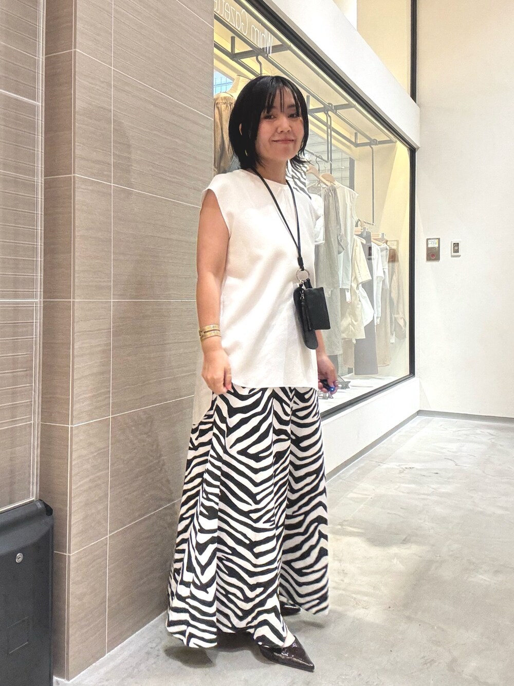 ホワイト系のシャツ/ブラウス、ホワイト系のスカート、ブラウン系のパンプスを着用したレディースの夏コーディネートの7枚目の写真