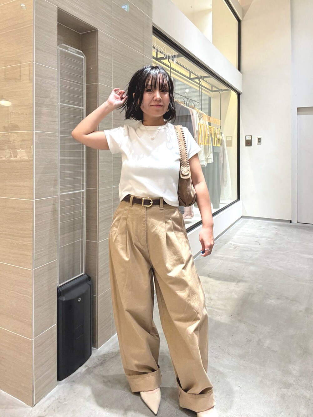 ベージュ系のチノパンツ、ホワイト系のTシャツ/カットソー、ブラウン系のショルダーバッグを着用したレディースの冬コーディネートの6枚目の写真