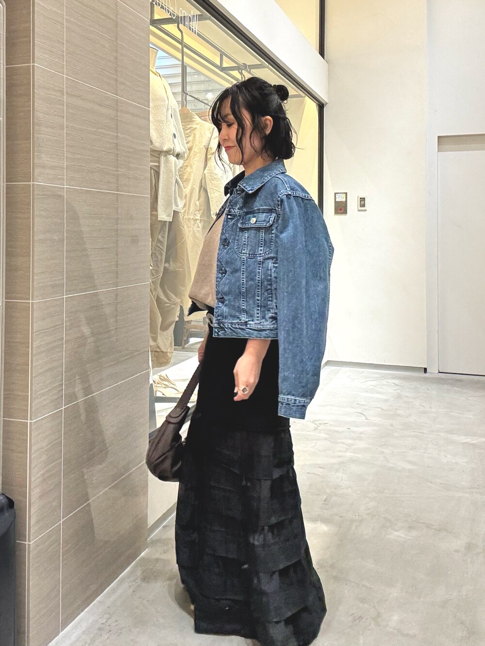 ブラック系のスカート、ブラウン系のショルダーバッグ、ブルー系のデニムジャケットを着用したレディースの冬コーディネートの4枚目の写真